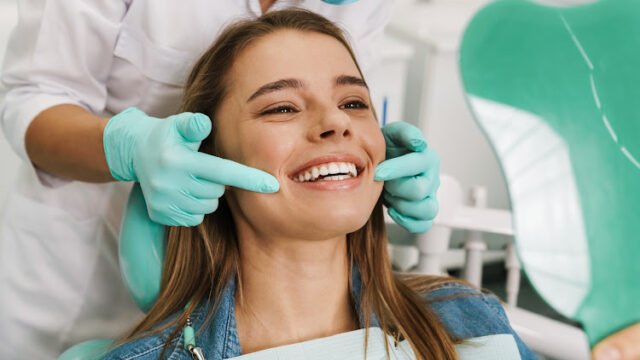 European young woman smiling while looking at mirror in dental clinic
