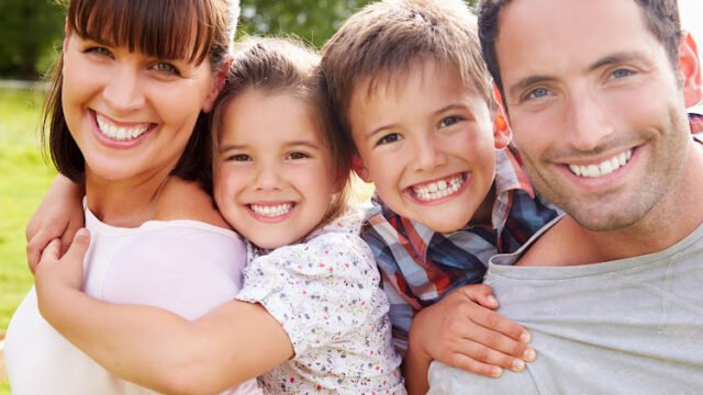Parents Giving Children Piggybacks Outdoors