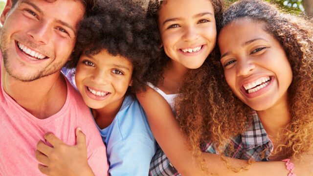 Parents Giving Children Piggyback Ride Outdoors